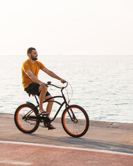 Fototapeta na wymiar Carefree man with bicycle riding at sunset having fun and smiling