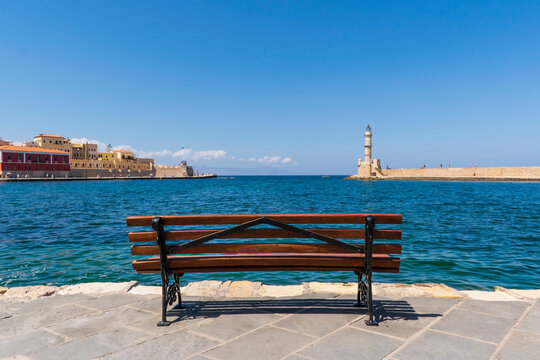 Bench on the Mediterranean coast in Greece. Stream lighthouse in the distance