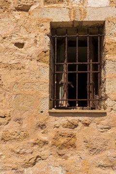 Window with old rusty lattice. Antique stone wall.