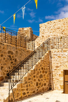 Stone ruined medieval steps. Yellow antique wall.Greek flags