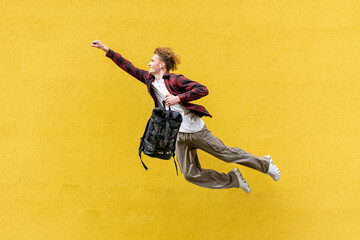young guy student with backpack flies forward and hurries to study, man in superman pose jumps and runs in the air