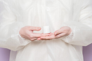 Hand of doctor holding jar of ointment, pills, tablets. Medicine bottle mockup