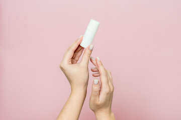 Hand holding white bottle. Drops for eye, nose or ear in hand on pink background. Pharmaceutical product.