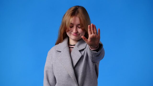 4k video of one gorl showing stop sign over blue background.
