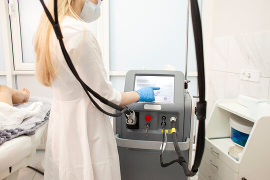 cosmetologist doctor in uniform adjusts equipment in cosmetology clinic for epilation procedure