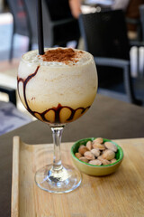 Glaass of iced frappuccino coffee with whipped cream, chocolate and ice cubes