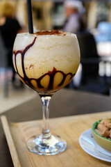 Glaass of iced frappuccino coffee with whipped cream, chocolate and ice cubes