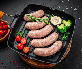 Raw homemade sausages with vegetables on a grill pan