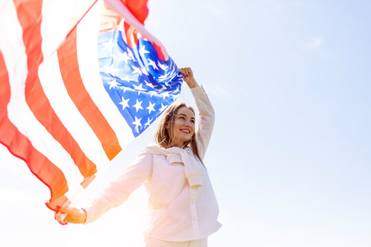 cute girl holding american flag and raising it to the sky, fourth of july concept - Powered by Adobe