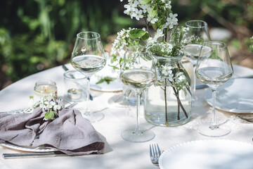 Romantic elegant luxury wedding table decor with white fresh spring blooming cherry apple tree flowers. Glass, candles, floral decoration for special marriage holiday event. No plastic zero waste