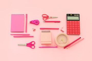 Flip paper calendar with alarm clock and stationery on pink background