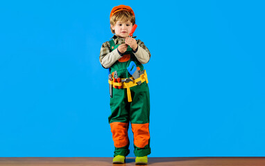 Builder boy in safety helmet and toolbelt with screwdriver. Child in uniform and hardhat with tool belt. Little repairman with screwdriver. Tools for repair. Child game. Little construction worker.
