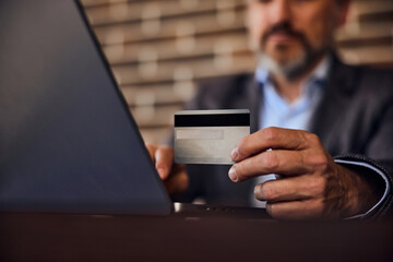 A close-up of a businessman's hands, holding his credit card and