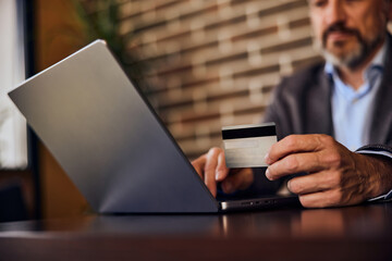 A busy restaurant owner using a laptop for online shopping and p