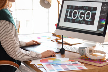 Female graphic designer working with tablet at table in office, closeup