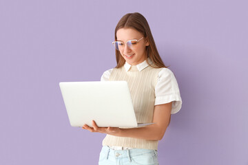 Female student studying with laptop on lilac background