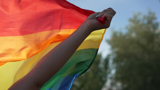 Video of an unrecognizable person's hand energetically raising a rainbow flag as a form of protest. LGTBIQ Concept
