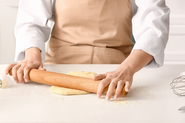 Woman rolling out dough for Italian Grissini at white table in kitchen