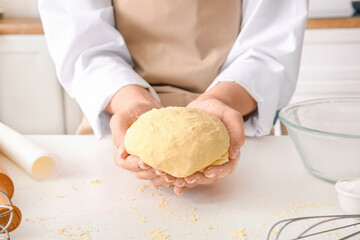 Woman kneading dough for Italian Grissini at white table in kitchen