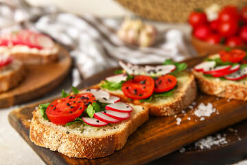 Board with delicious radish bruschettas on white table