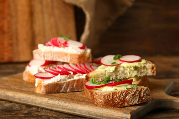 Board with delicious radish bruschettas on wooden table