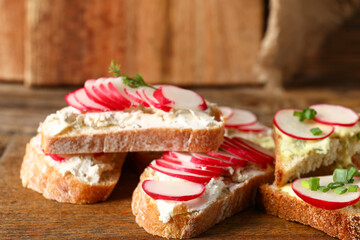 Board with delicious radish bruschettas on wooden table