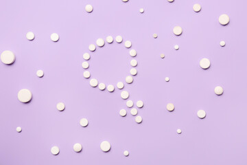 Symbol of woman made with hormonal pills on lilac background