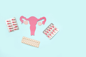 Paper uterus with hormonal pills on blue background