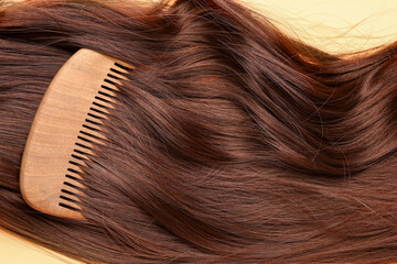 Brown hair with comb on yellow background