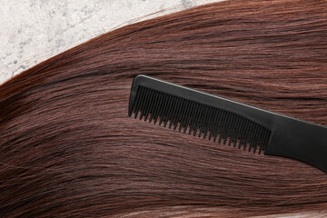 Obraz premium Brown hair with brush on grunge background, closeup