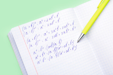 Copybook with maths formulas and pen on green background