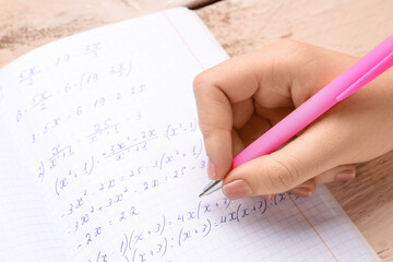 Woman writing maths formulas in copybook with pen, closeup