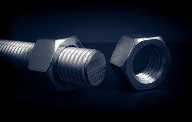 Metallic nuts with threaded rod. Low-key concept picture taken in studio with soft-box and dark...