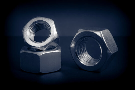 Metallic nuts. Low-key concept picture taken in studio with soft-box and dark background representing some mechanical components.