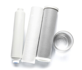 Glass of liquid and water filter cartridges on grey background