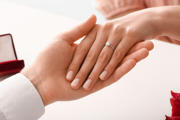 Engaged couple holding hands at table, closeup
