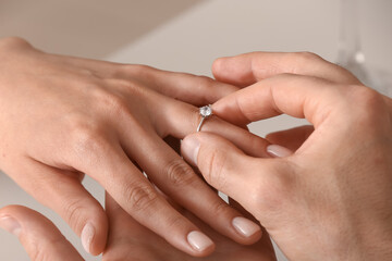 Man putting engagement ring on woman's finger, closeup