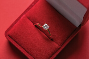 Box with engagement ring and red background, closeup
