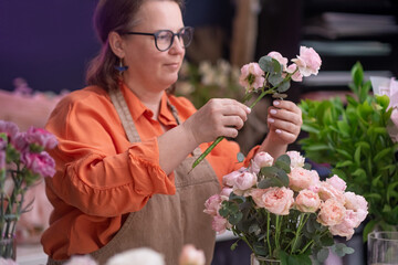 female flower decorator floral designer working on laptop at shower store studio. bouquets around, flower business