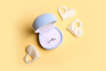 Box with engagement ring and hearts on beige background