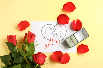 Box with engagement ring, card and roses on beige background