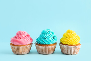 Tasty colorful cupcakes on blue background