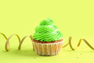 Tasty cupcake and confetti on green background