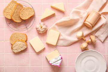 Processed cheese, bread and vegetables on pink tile background