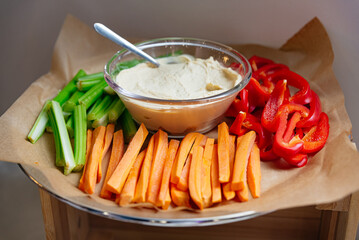 fresh vegetable sticks and Hummus dip. Fresh, crunchy vegetables like celery and carrots are paired with bell peppers for a healthy snack dip. Perfect for fast food on-the-go or maintaining wellbeing!