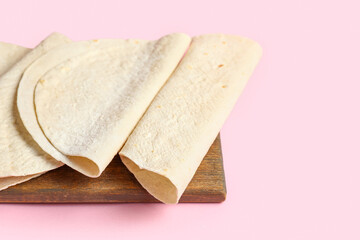 Board with thin lavash on pink background