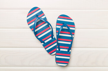 Bright flip flops on wooden background, top view