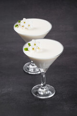 Vanilla cream dessert, Panna Cotta, decorated with small white flowers, in a martini glass. Dark gray background
