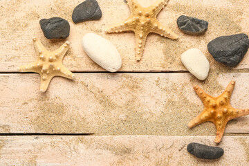 Sand with starfishes and shells on beige wooden background