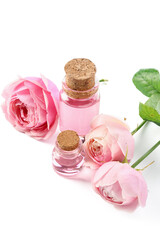 Bottles of cosmetic oil with rose extract and flowers on white background